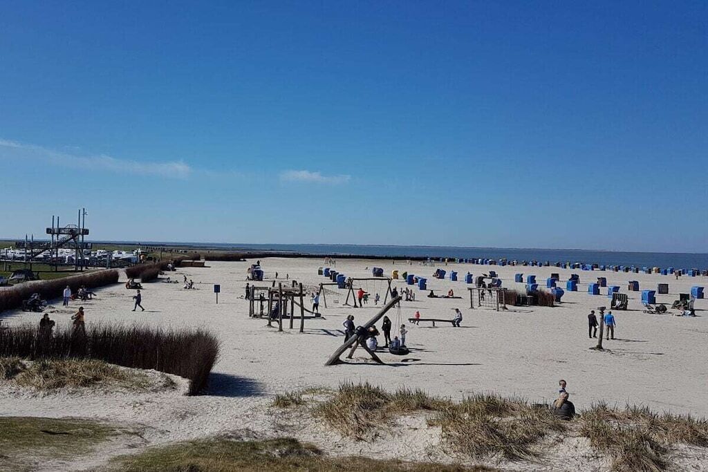 Ein Strand mit Menschen, einem Spielplatz und Liegestühlen.