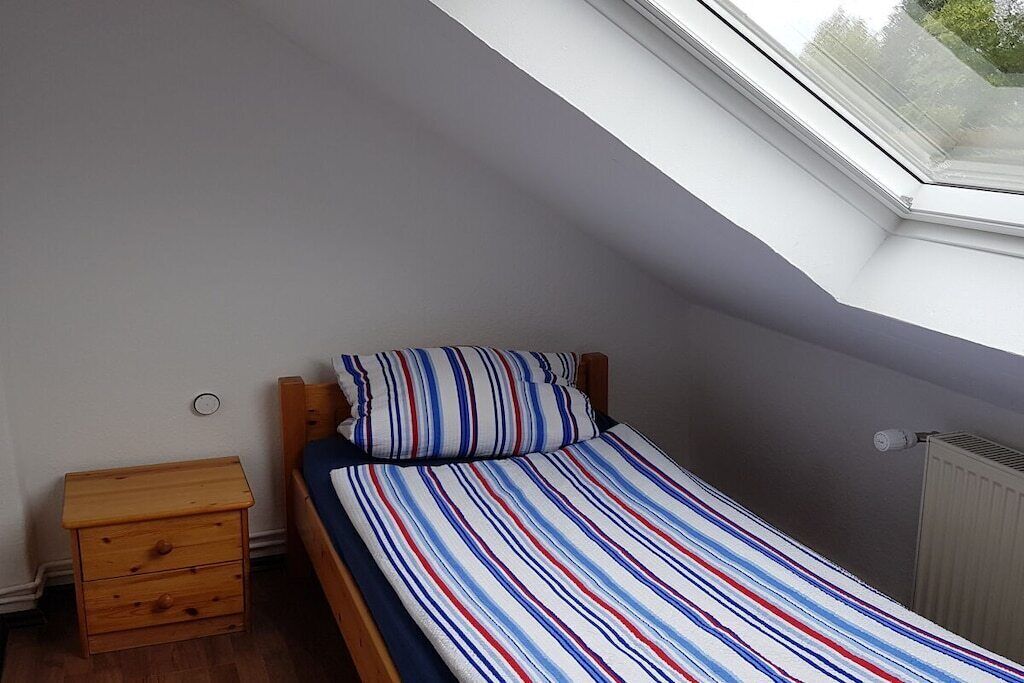 Ett litet rum med en enkel säng, ett sluttande tak och ett takfönster.