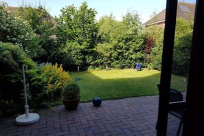 Ein Patio mit Pflasterboden, einem Blumentopf und einer Metallskulptur.