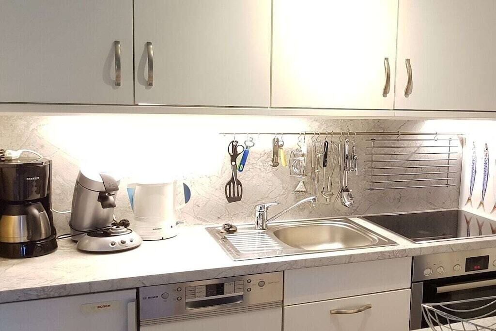 A kitchen with white cabinets, a Bosch dishwasher, a coffee maker, and a kettle.