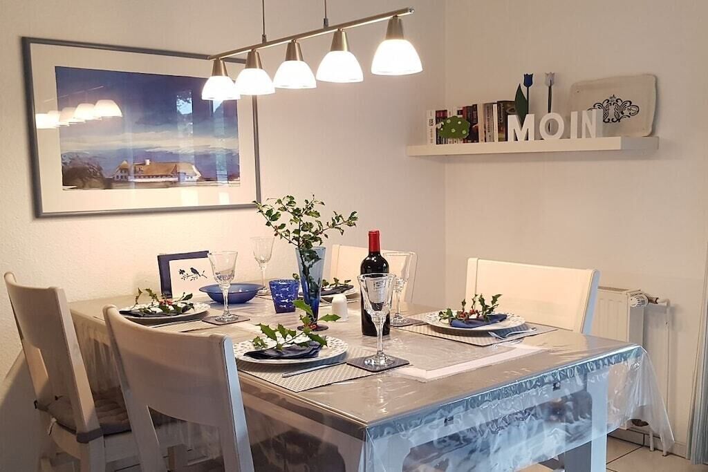 Una mesa de comedor servida con platos, vasos y un florero.