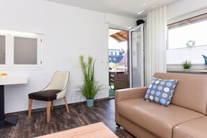 Una sala moderna con un sofá, un sillón, una mesita y una planta en maceta.