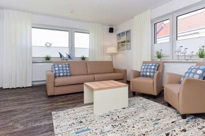 A modern living room with a beige sofa, a matching armchair, a coffee table, and a patterned rug. - Holiday apartments "Seagull 2" (Esens-Bensersiel)