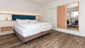 Una camera d'albergo con un letto, un comodino e uno specchio.