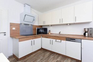 A modern kitchen with white cabinets, a microwave, a coffee maker, and a dishwasher. - Holiday apartments "Seagull 2" (Esens-Bensersiel)