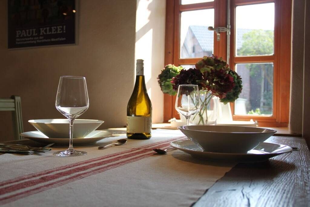 A table set with a wine bottle, two wine glasses, and a bowl of flowers.