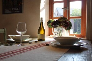 Une table dressée avec une bouteille de vin, deux verres à vin et un vase de fleurs.