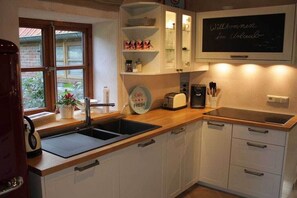 Eine Küche mit weißen Schränken, einer schwarzen Arbeitsplatte, einer Kaffeemaschine und einer Tafel mit einer Willkommensbotschaft.