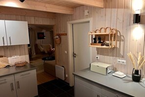 A modern kitchen with wooden paneling, a built-in oven, and a countertop with a toaster. - Holiday home with 3 bedrooms (Wesselburenerkoog)