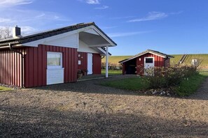 A red building with a white door and a small porch. - Holiday home with 3 bedrooms (Wesselburenerkoog)