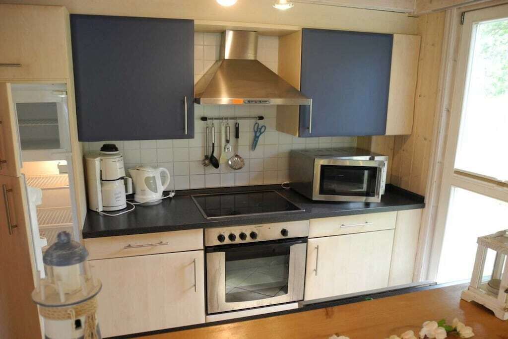 A kitchen with a stove, microwave, and oven, with cabinets and a window.