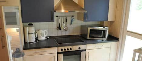 A kitchen with a stove, microwave, and oven, with cabinets and a window.