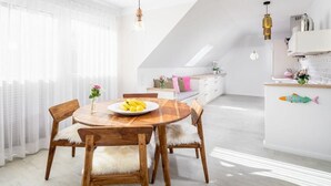 Cozinha moderna com armários brancos, mesa de jantar de madeira e bancada clara.