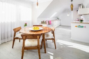 Een moderne keuken met witte kasten, een houten eettafel en een wit aanrecht.
