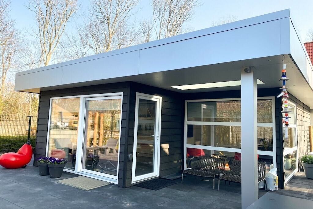 A modern house with a flat roof, large sliding glass doors, and a covered patio area.