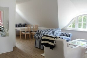 Ein modernes Wohnzimmer mit einer Couch, Sesseln und einem Glastisch.