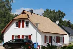A white building with a sloped roof, red shutters, and a satellite dish. - Holiday apartment with 1 bedroom (Koserow)