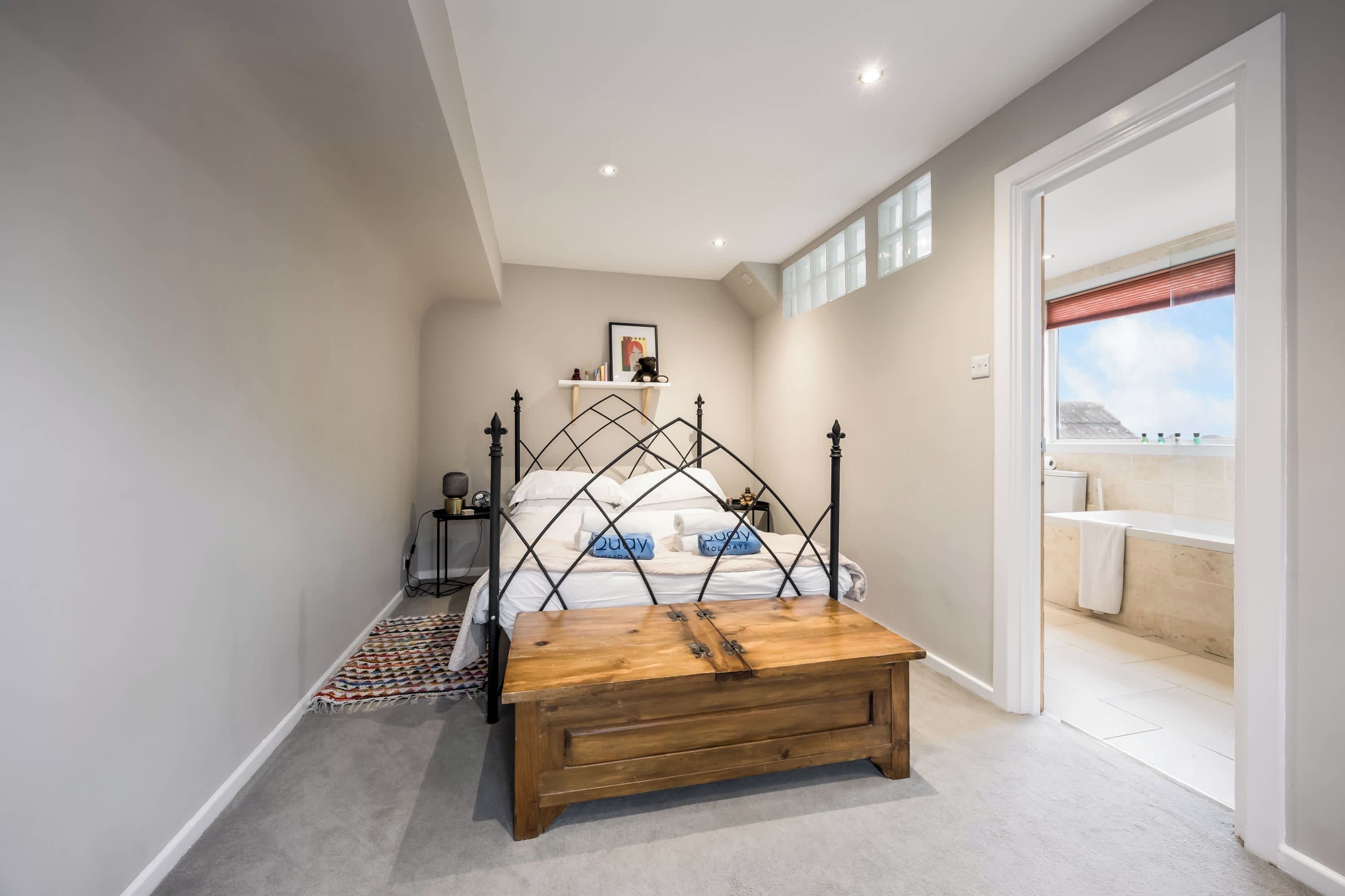A bedroom with a bed, bedside table, and a view of the bathroom.