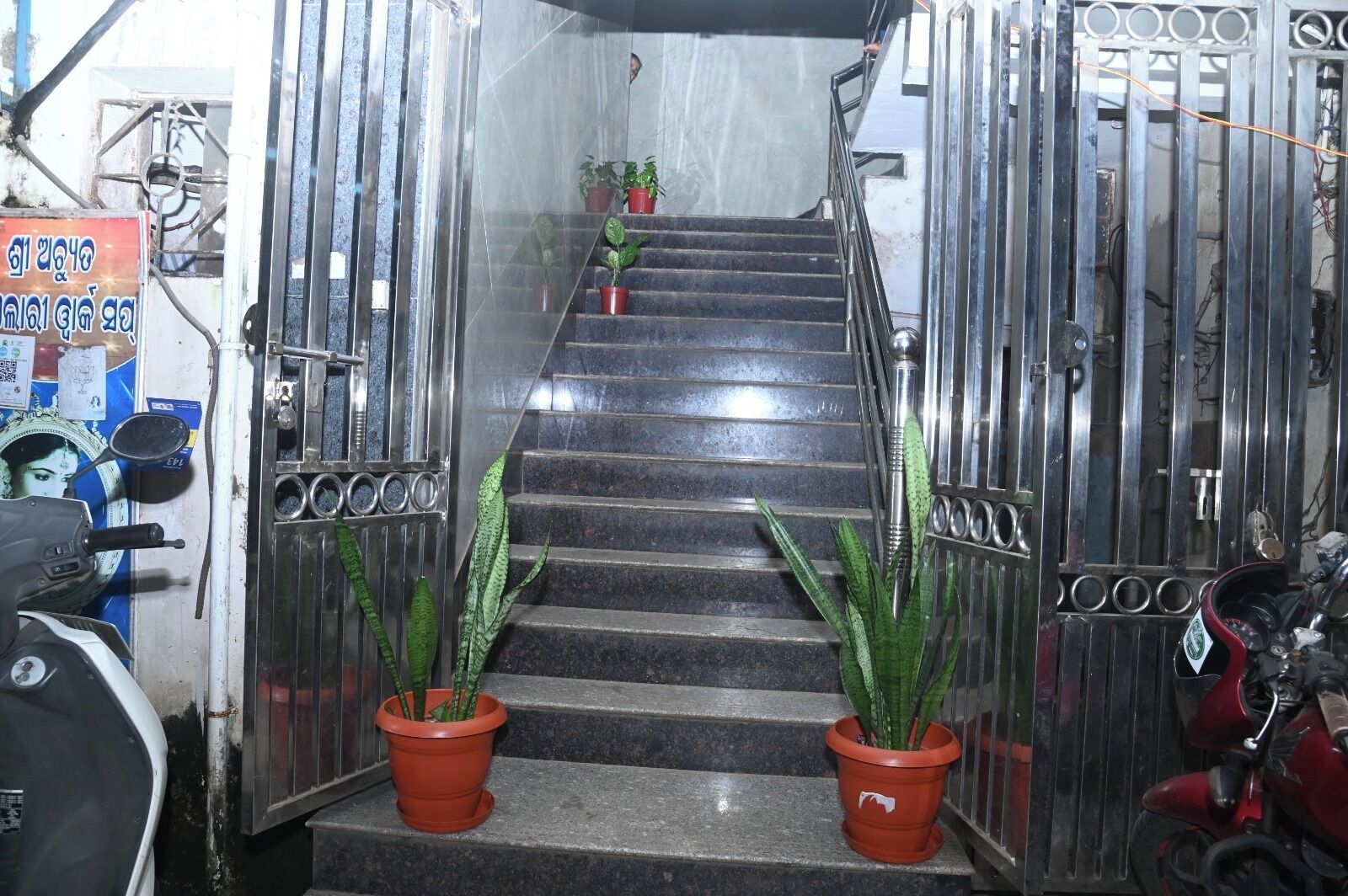 A staircase with metal railings and potted plants at the bottom.