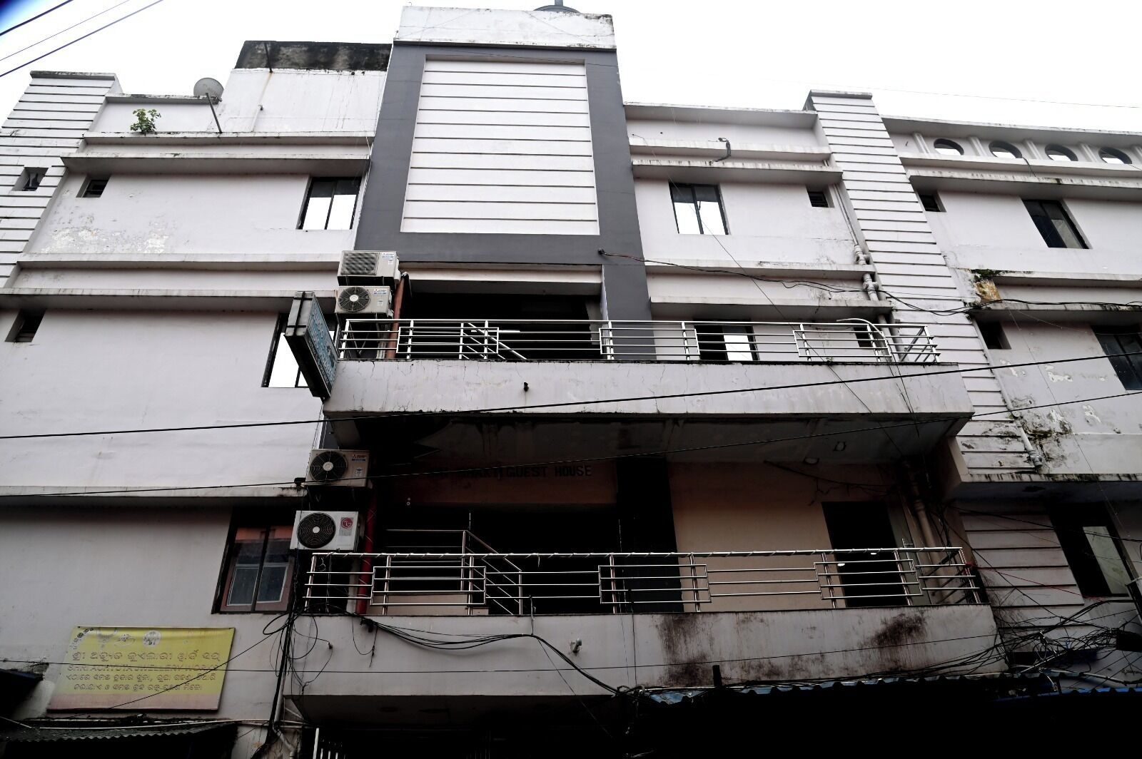 Um edifício com vários andares, varandas, aparelhos de ar condicionado e uma placa indicando uma residência para hóspedes.