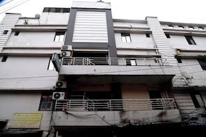 Un edificio de varios pisos con balcones, unidades de aire acondicionado y un letrero que indica una casa de huéspedes.
