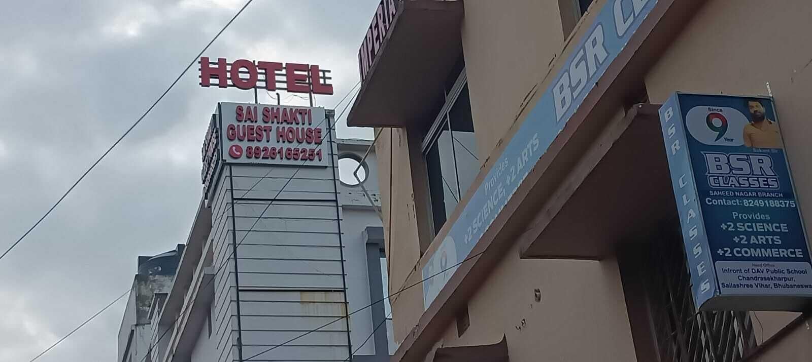 A hotel sign with a guest house and contact number.
