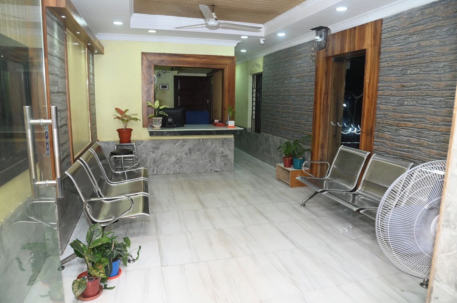 A reception area with a marble counter, metal chairs, and potted plants.