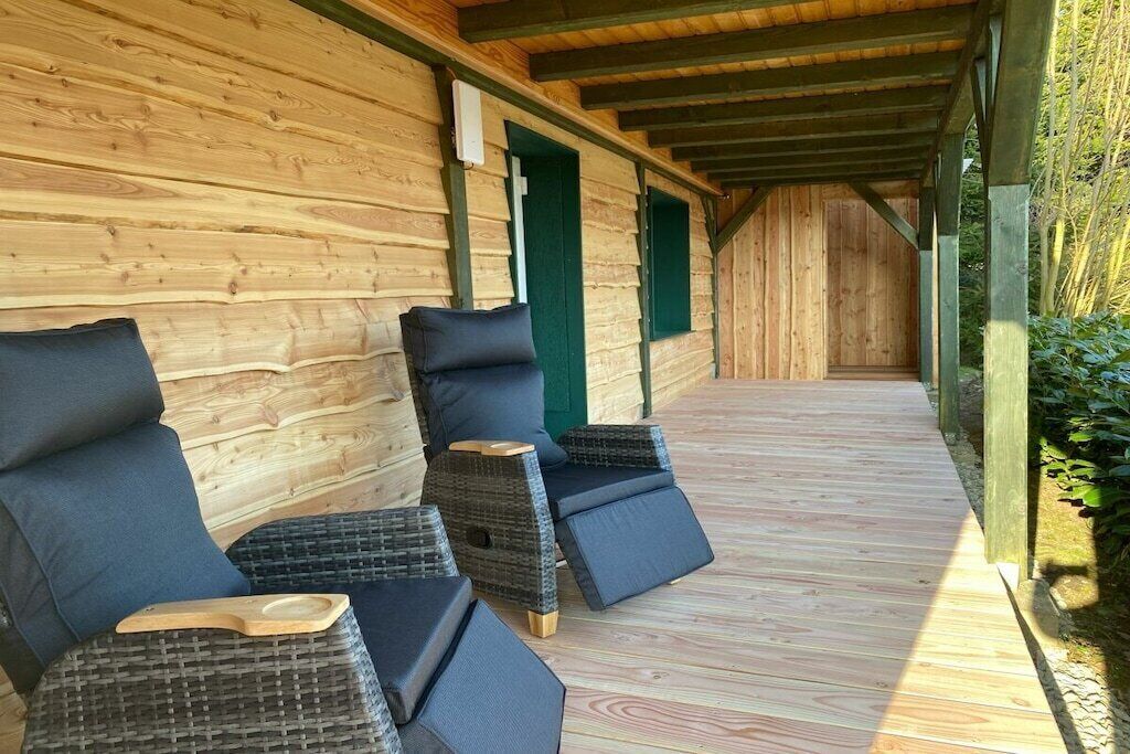 Een overdekt terras met rieten stoelen en een houten vloer.