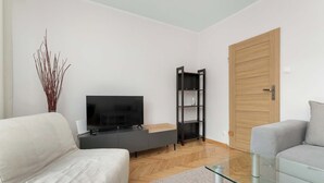 Een moderne woonkamer met een flatscreen televisie, een zwarte boekenkast, een houten deur en twee banken.