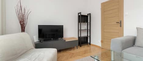 Una sala de estar moderna con un televisor de pantalla plana, un mueble de estanterías negro, una puerta de madera y dos sofás.