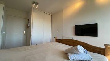 Ein Hotelzimmer mit einem Bett, einem an der Wand befestigten Fernseher und einer Tür mit Lichtschalter.