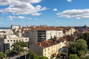 Un paisaje urbano con una mezcla de edificios modernos y tradicionales, cielo despejado y una vista distante del mar.