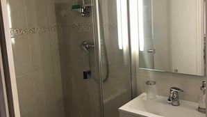 A bathroom with a glass-enclosed shower, a vanity with a mirror, and a sink.