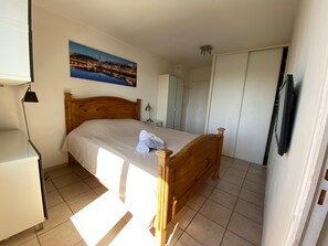 Une chambre à coucher avec un lit en bois, une table de chevet, une lampe, un tableau accroché au mur et une armoire.