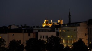 A nighttime cityscape with illuminated buildings and a prominent cathedral in the background.