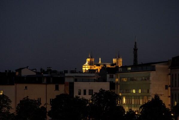 Un paisaje urbano nocturno con edificios iluminados y una catedral destacada al fondo.