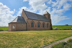 Eine große Backsteinkirche mit einem markanten Turm und Rundbogenfenstern.