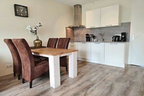Eine moderne Küche mit weißen Schränken, einem Holztisch und braunen Stühlen.