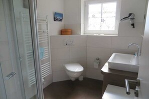 Ett litet badrum med toalett, handfat och ett fönster.