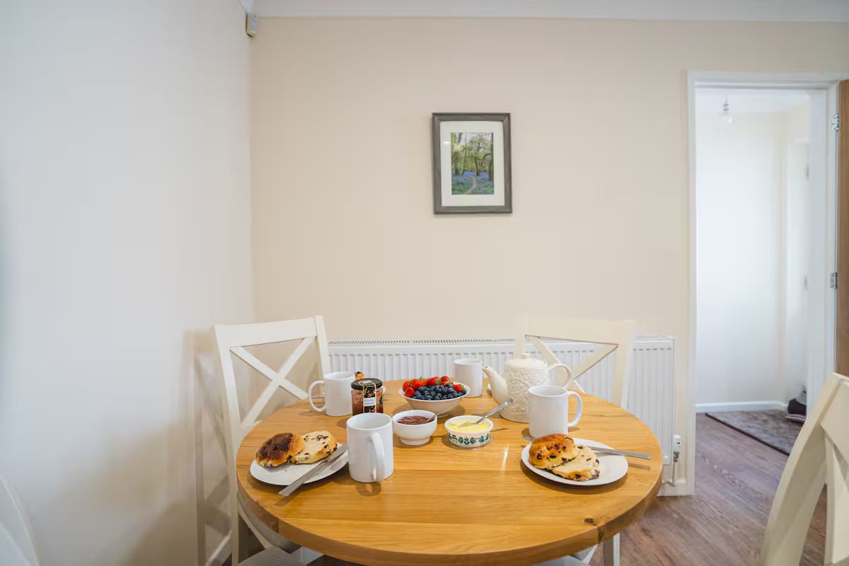 Ein Esstisch mit Frühstücksgebäck, Stühlen, einem Heizkörper und einem gerahmten Bild an der Wand.