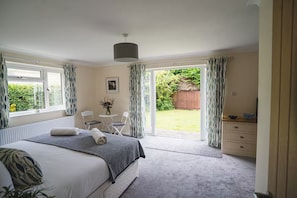 Ein Schlafzimmer mit Bett, Schreibtisch und Blick auf einen Garten.