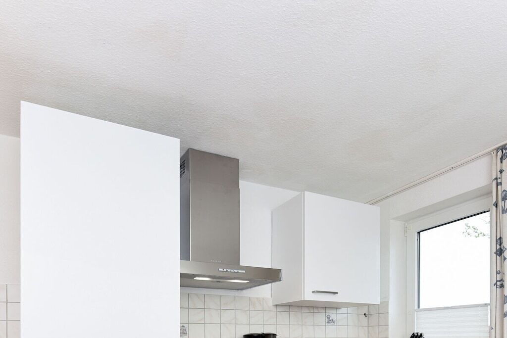 Una cocina moderna con gabinetes blancos, una campana de acero inoxidable y una ventana con vistas.