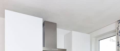 Una cocina moderna con gabinetes blancos, una campana de acero inoxidable y una ventana con vistas.