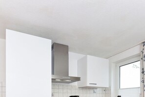 Uma cozinha moderna com armários brancos, coifa de aço inoxidável e janela com vista.