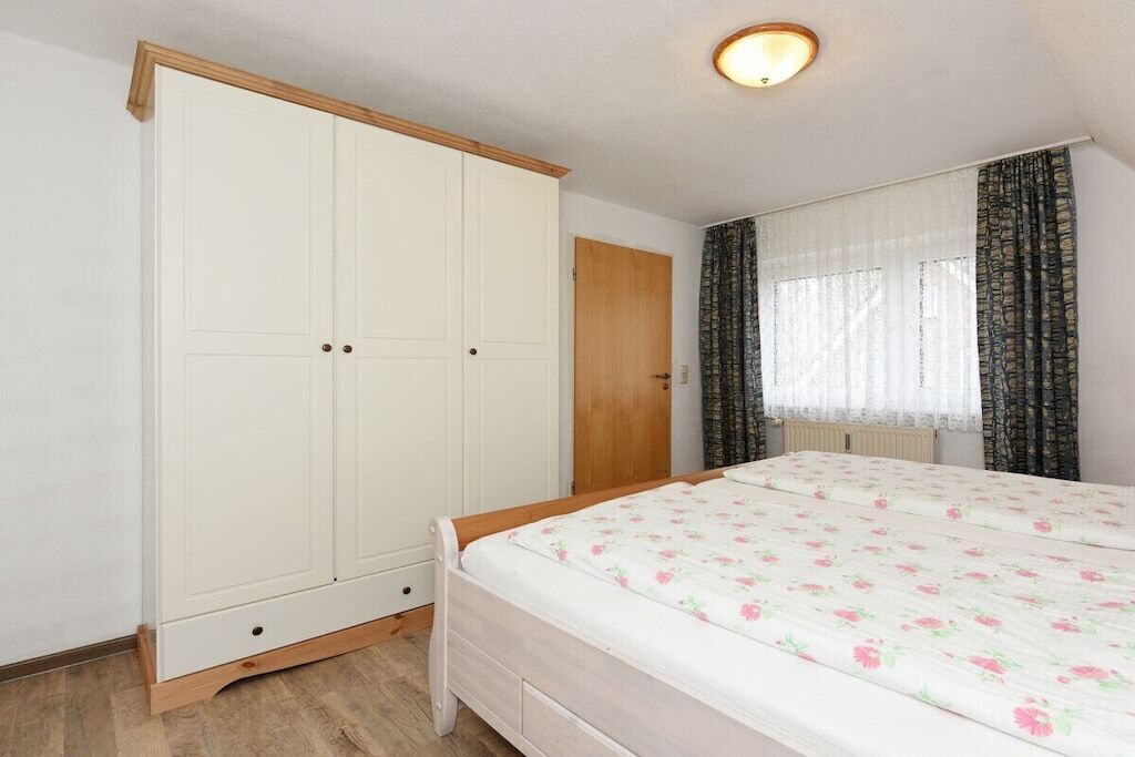 A bedroom with a bed, a wardrobe, and a window with curtains.