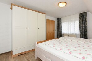 A bedroom with a bed, a wardrobe, and a window with curtains. - Holiday apartment "Krabbe" (Esens-Bensersiel)