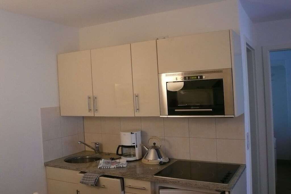 Eine kleine Küche mit einem eingebauten Ofen, einer Kaffeemaschine und einem Wasserkocher auf der Arbeitsfläche.