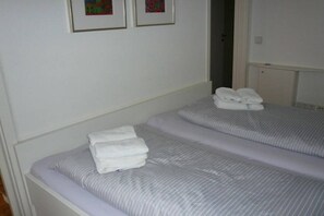 A hotel room with two beds, each with a striped bedspread and a stack of folded towels. - 7 in the Emspirat house (Norderney)