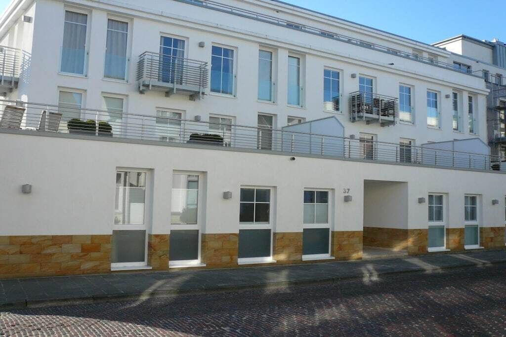 A multi-story residential building with a flat facade, balconies, and a stone base.