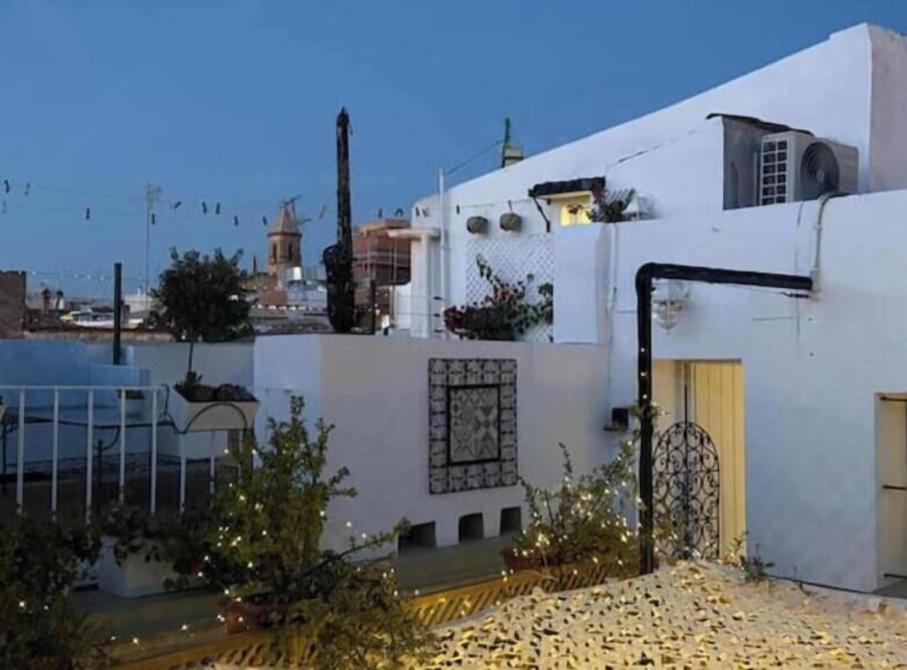 A white building with a gated entrance, a small window, and a decorative metal gate.